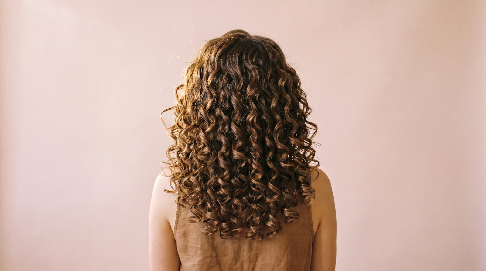 The same head after a curly cut: defined, glossy spiral curls with a sculpted shape